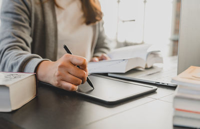 Midsection of woman using mobile phone while sitting on table