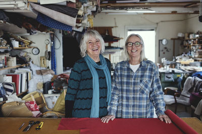 Portrait of happy colleagues standing by shelf at workshop