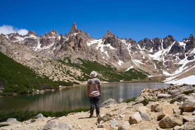 Rear view of man standing on rock against lake