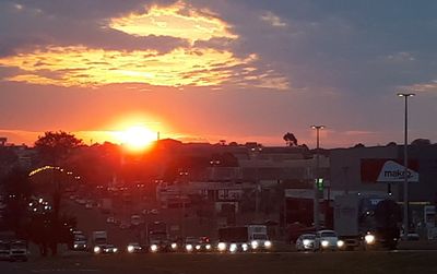 Cars on street against sky at sunset