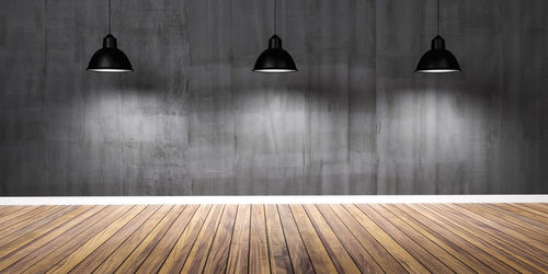View of illuminated lamp on floor against wall