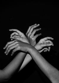 Midsection of woman with hands against black background