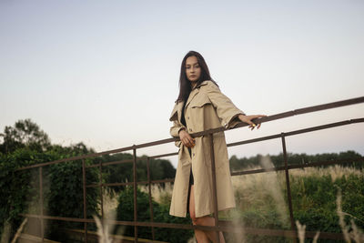 Woman standing on a metal bridge in a raincoat