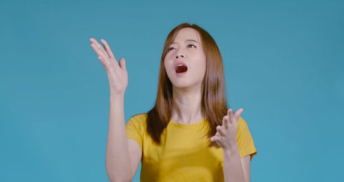 Young woman standing against blue background