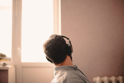 Man looking through window while listening music working at home