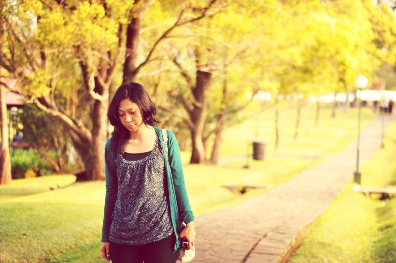 casual clothing, person, lifestyles, tree, young adult, looking at camera, leisure activity, standing, portrait, front view, smiling, three quarter length, young women, focus on foreground, waist up, park - man made space, happiness