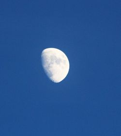 Low angle view of moon against blue sky