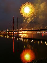 Firework display over river against sky at night