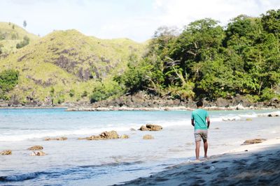 Full length rear view of man walking on beach