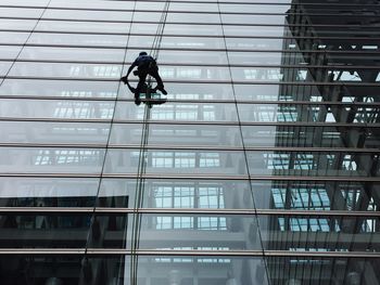 Low angle view of man cleaning glass building