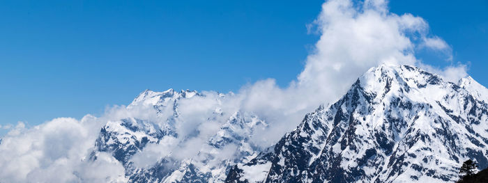 Low angle view of snowcapped mountains against blue sky