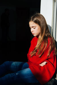 Depressed girl sitting on window sill