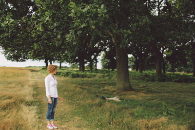 Full length of woman standing on grass by trees