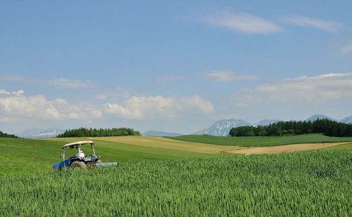 Tractor on rural field against sky