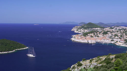 High angle view of sea and mountains against blue sky