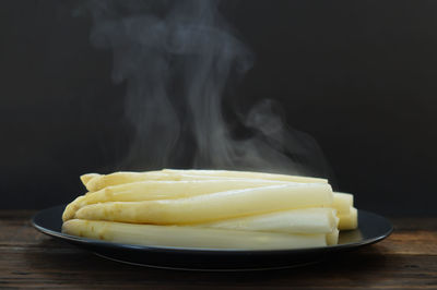 Close-up of bread in plate on table against black background