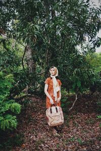 Woman standing against trees in forest