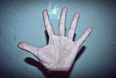 Cropped hand of man gesturing against wall