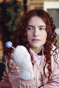 Woman with curly redhead holding lollipop