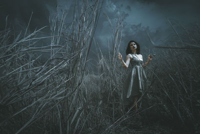 Portrait of young woman standing in grass at night