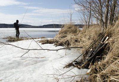 Side view of person fishing in lake during winter