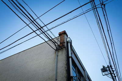 Low angle view of electricity pylon against blue sky