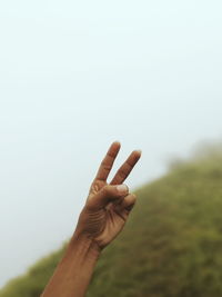 Cropped hand of person gesturing against sky