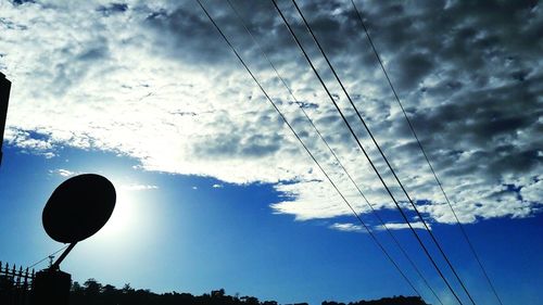 Low angle view of silhouette power lines against sky