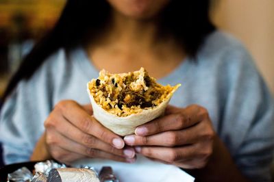 Midsection of woman holding burrito