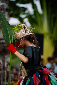 Rear view of woman with leaves outdoors