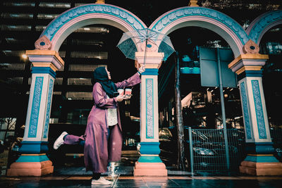 Rear view of woman standing against illuminated building