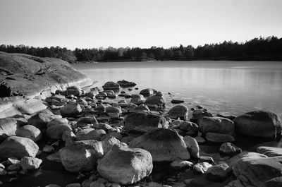 Rocks by sea against clear sky