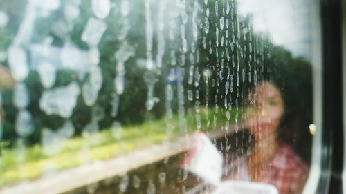 Close-up of woman seen through wet glass window