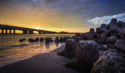 Bridge over water against sky during sunset