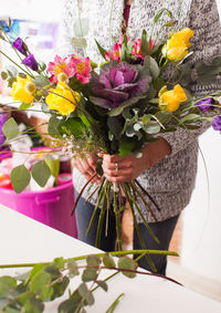 Low section of woman holding flower bouquet