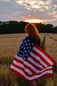 Rear view of woman with american flag on field