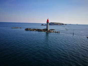 Lighthouse on sea against sky