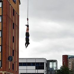 Low angle view of man jumping on building against sky