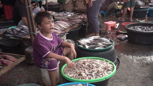 Rear view of girl having food at market