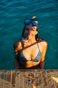 Woman standing by swimming pool against sea