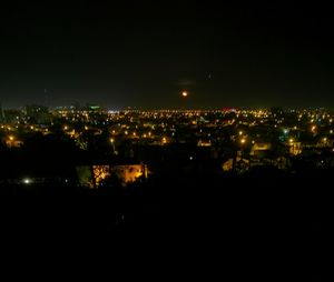 Illuminated cityscape against sky at night