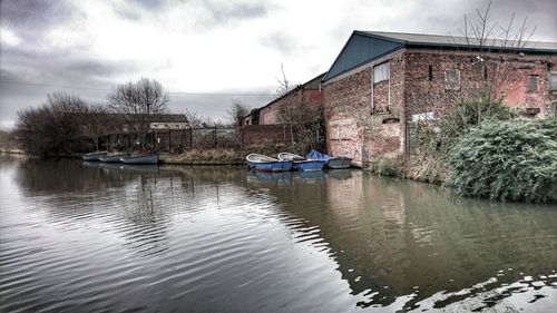 Houses by river against sky