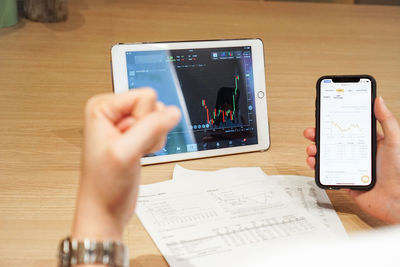 Midsection of woman holding smart phone on table