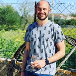 Portrait of smiling mid adult man standing against fence