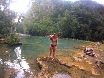 Young woman standing on rock against trees