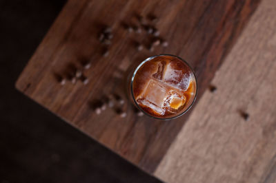 Tall glass of cold brew iced coffee on a wooden coffee table