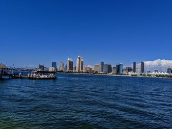 Sea by buildings against clear blue sky