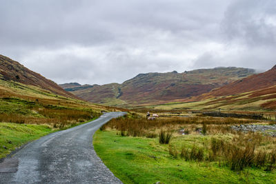 Road leading towards mountains against sky