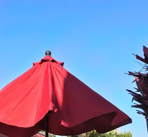 Low angle view of red umbrella against clear blue sky