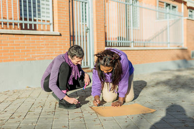 Side view of woman sitting on footpath